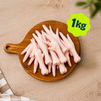 A pile of Birmingham Raw chicken feet dog treats sold by the kilogram, displayed on a round wooden cutting board over a light wood kitchen unit.