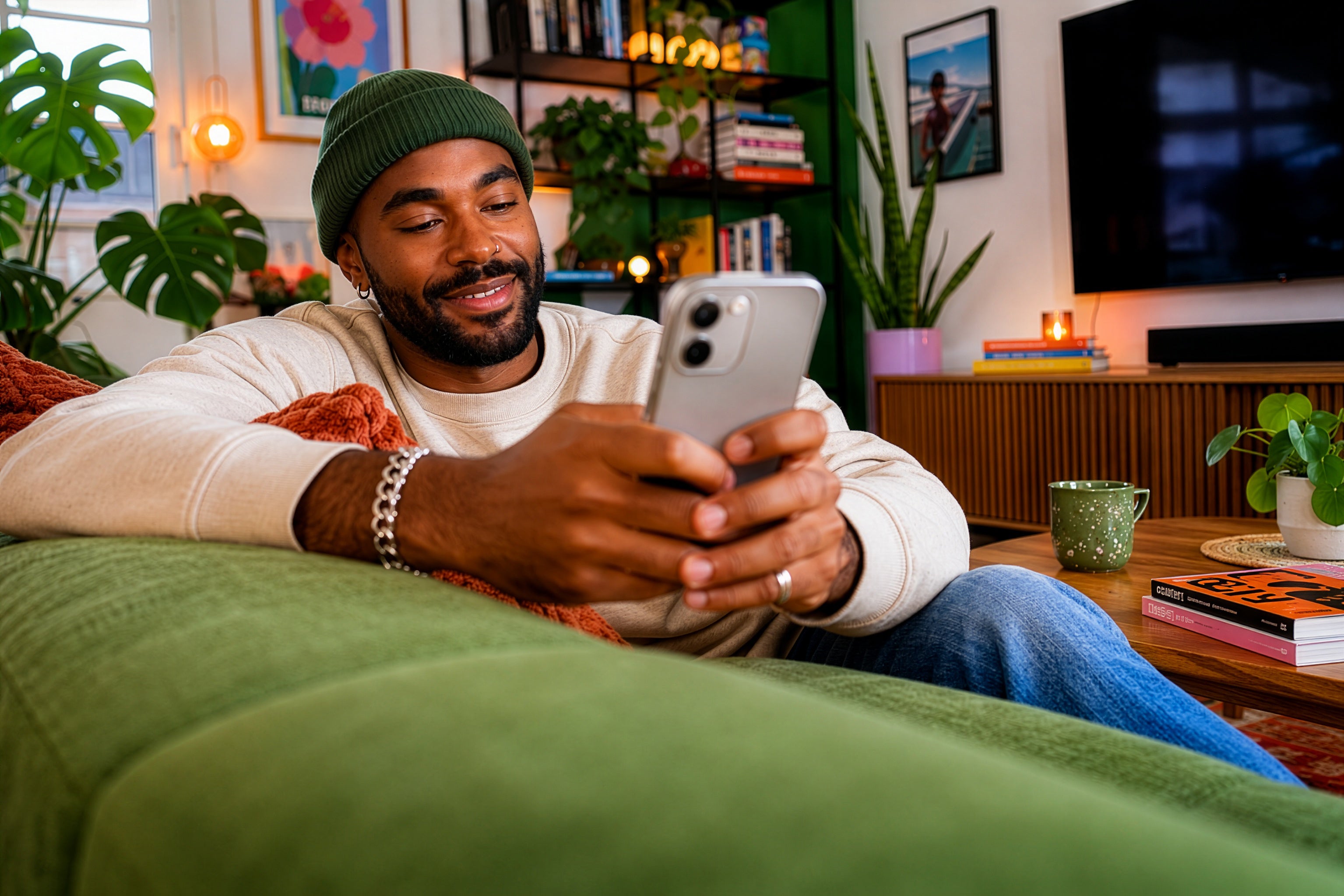 Man sitting on a couch using a smartphone in a cozy living room.